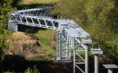 Pipe bridge by FLI Structures  winding around trees across a valley